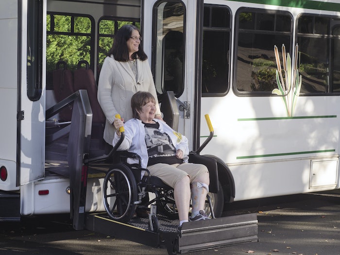 Rehabilitation specialist helps a guy to do exercises for recovery from injury, who is sitting in a wheelchair with a corset around his neck. Concept of physical therapy for people with disabilities